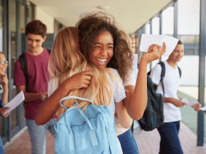 Girl smiling and hugging friend at school without worry about the future