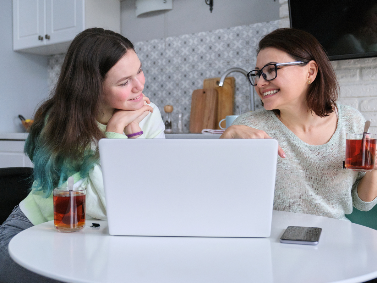 mother and daughter smiling in the kitchen in front of laptop