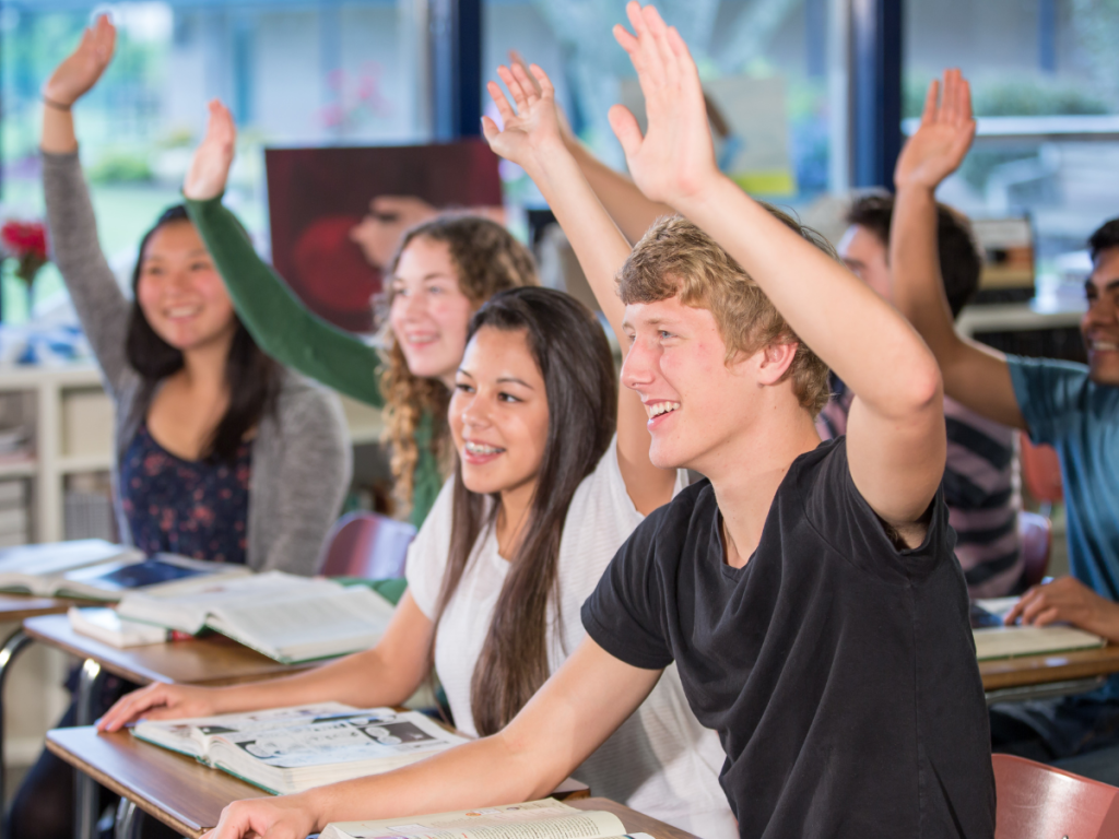 Students raising their hands in the classroom