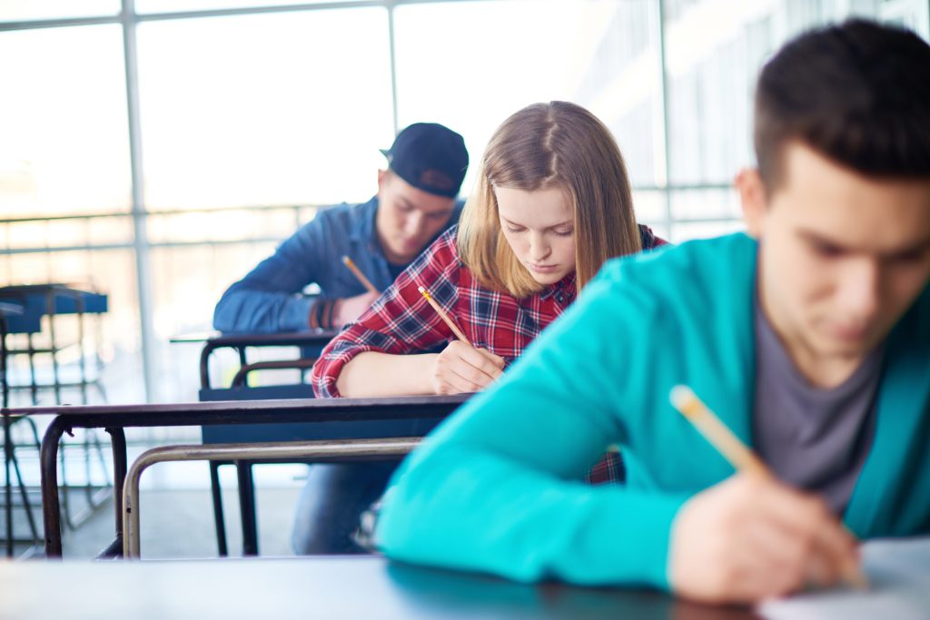 male and female teens taking exams